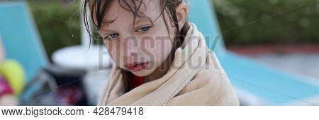 Little Frozen Girl Sits On Beach In Towel