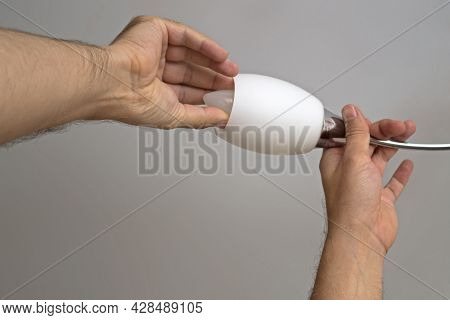 The Left Man's Hand Holds The Arm Of The Chandelier The Right Hand Screws Or Unscrews Energy-saving 