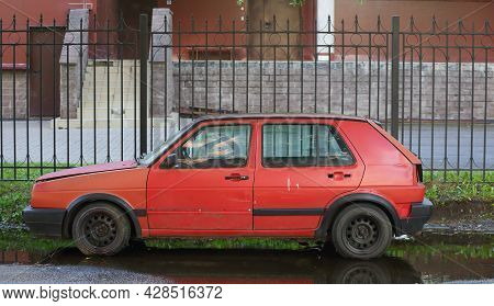 An Old Red Car Is Parked At A Lattice Fence, Ulitsa Antonova-ovseenko, St. Petersburg, Russia, Iavgu