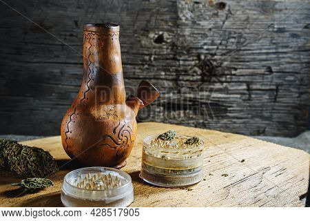 Old Brown Steamung Bong And Open Cannabis Grinder With Chopped Marijuana Weed And Medical Cannabis B
