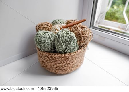 Yarn In A Knitted Basket On A White Background With Hooks. Yarn Of Different Colors. The Concept Of 
