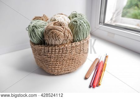 Yarn In A Knitted Basket On A White Background With Hooks. Yarn Of Different Colors. The Concept Of 