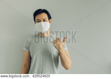 Normal Face Of Asian Man Wearing White Hygienic Mask In Grey T-thirt With Copy Space.