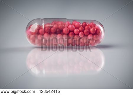 Close up of single capsule pill beads. Single dose drug prescription or medicine.