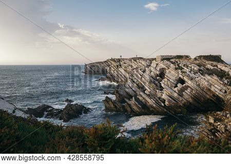 A Beautiful Shot Of A Bush-covered Coastline With Tilted Sandstone Rock Formations In Peniche, Portu