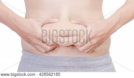 A Front View Of A White Man In Gray Pants Squeezing His Stomach With Both Hands To Show His Fatness.