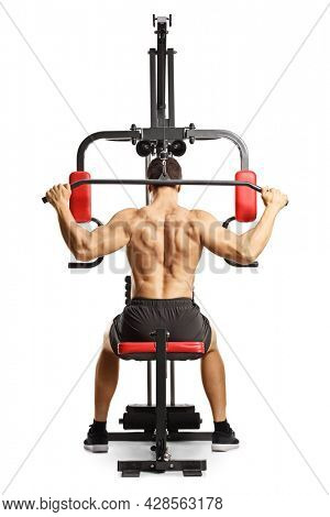 Shirtless musuclar man exercising back muscles with a bar on a fitness machine isolated on white background