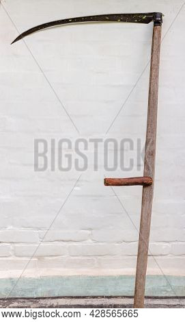 Old Scythe With Wooden Snaith And Blade Covered With Small Grass Slices On A Background Of The White
