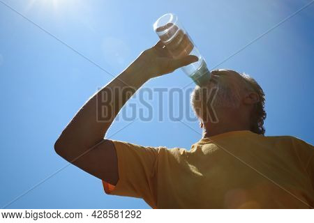 Senior Man Drinking Water To Prevent Heat Stroke Outdoors, Low Angle View