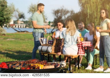 Group Of Friends Having Party Outdoors, Focus On Barbecue Grill With Food
