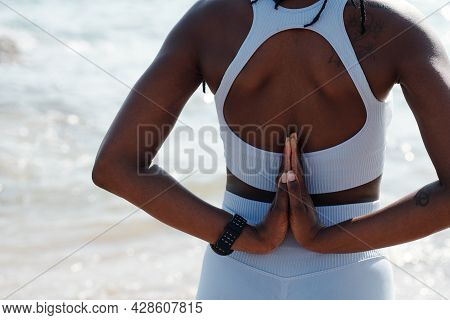 Cropped Image Of Sportswoman Doing Reverse Prayer Pose When Standing On Beach