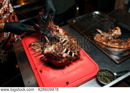 Chev Cuts Juicy Cooked Meat, Separating The Meat From The Bone With A Knife.