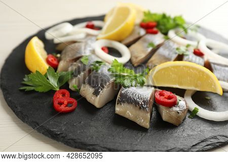 Slate Plate With Sliced Salted Herring Fillet, Parsley,  Chili Pepper, Onion Rings And Lemon On Ligh