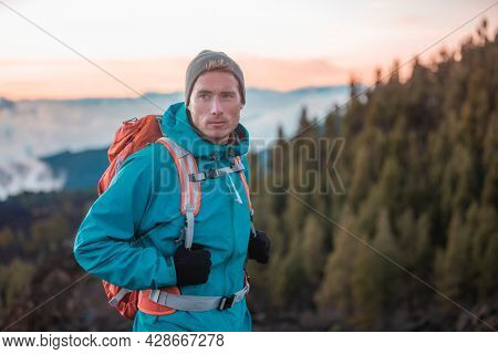 Man hiker hiking in mountain forest wearing cold weather accessories, wind jacket and backpack for camping outdoor. Guy portrait lifestyle.