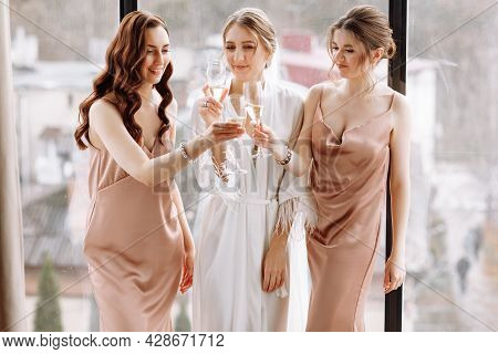 Morning Of Bride. Gorgeous Bride With Best Bridesmaids Are Holding Glasses And Drinking Champagne In