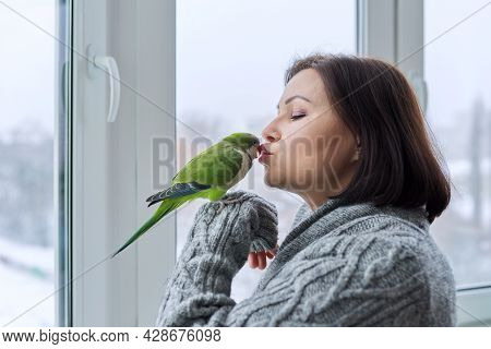 Middle Aged Woman And Parrot Together, Female Bird Owner Talking Kissing Green Quaker Pet