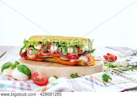 Fresh Baguette Sandwiches With Ham, Mozzarella Cheese, Tomatoes And Fresh Lettuce On Wooden Cutting 