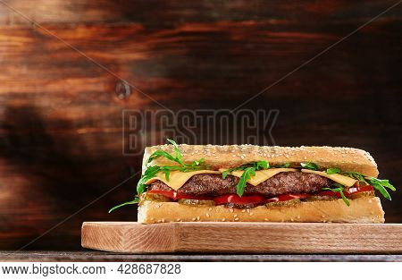 Grilled Juicy Baguette Sandwich With Cutlet And Fresh Vegetables On Wooden Background. Sandwich Menu
