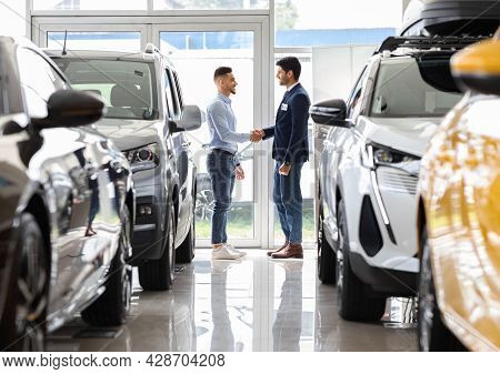 Wealthy Middle-eastern Man Shaking Sales Manager Hand In Auto Showroom