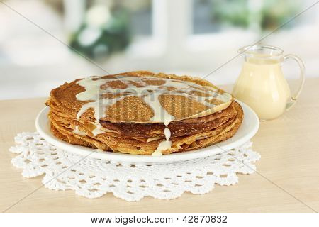 หวาน pancakes บนแผ่นกับนมข้นบนโต๊ะในห้องครัว