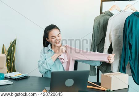 Young Asian Entrepreneurs Are Picking Up Shirts To Compare Proportions For Customers To View Them On