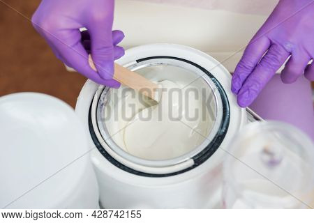Hands With Violet Gloves Is Mixing With Spatula Melted Wax Inside In Electric Wax Warmer Bowl