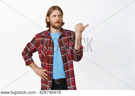 Confused Blond Man Pointing Right With Frowned Face, See Smth Strange, Point At Advertisement With P