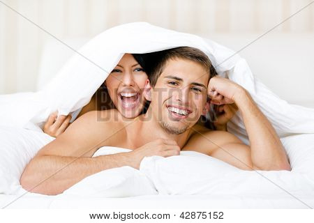 Nahaufnahme eines Paares spielen im Bett. Bedeckt mit Decke Frau liegend auf der Rückseite des Mannes