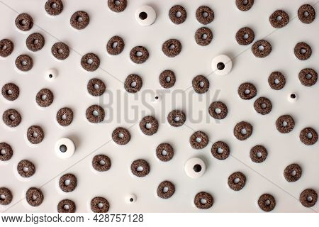 A Lot Of Black Rings Cerial And Candy Monsters Eyes In White Milk, Breakfast Background. Concept Hal