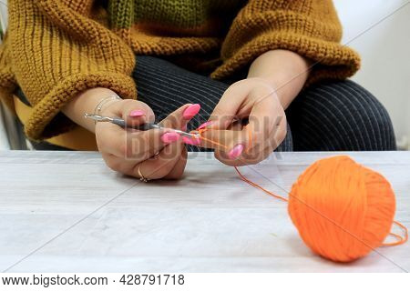 The Concept Of Crocheting Products.yellow Thread And A Hook In Women's Hands Against The Silhouette 