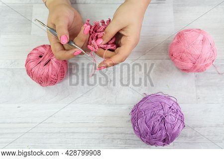 The Concept Of Crocheting Products.crochet Hook In Women's Hands With A Pink Manicure Among Multi-co