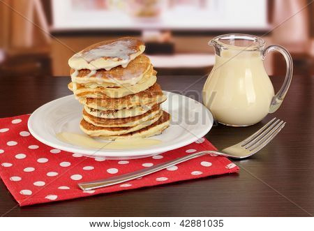 หวาน pancakes บนแผ่นกับนมข้นบนโต๊ะในห้อง