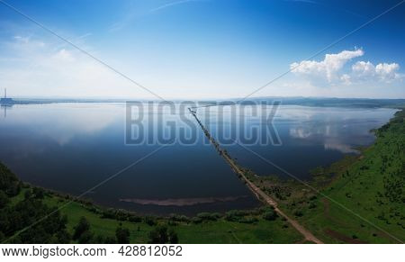 Beryozovskoye reservoir - cooling reservoir of Beryozovskaya GRES. Aerial drone view of lake landscape with road in sunny summer. Berezovskaya GRES is a thermal power plant in the town of Sharypovo