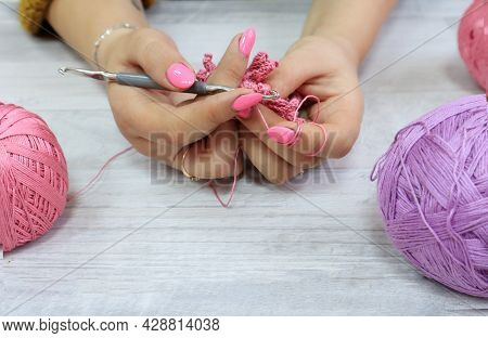 The Concept Of Crocheting Products.crochet Hook In Women's Hands With A Pink Manicure Among Multi-co