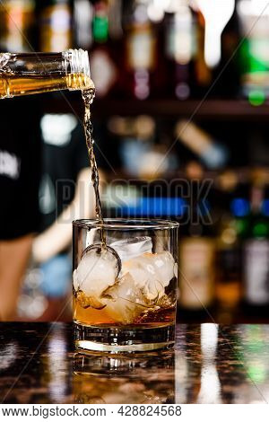 Whiskey Is Poured Into Glass. Glass Of Whiskey On Bar Counter In Restaurant. High Quality Photo