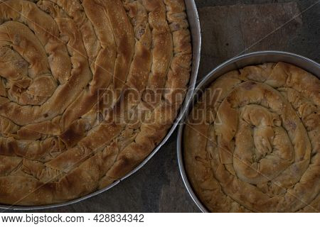 Baked Homemade Traditional Greek Cheese Twist Pie In Two Iron Oven Pan With Filo, Spinach, Mizithra 