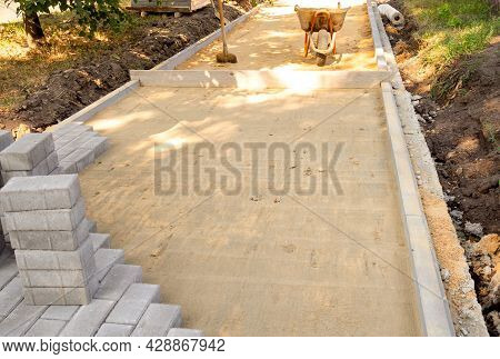 Paving Slabs Or Paving Stones Are Laid Out On The Sand Between The Curbstone. Process Of Laying Side