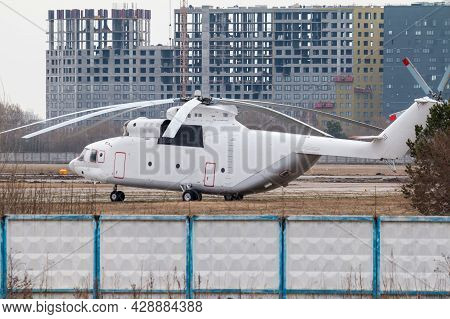 Large White Cargo Helicopter At The Landing Site Surrounded By Buildings Under Construction