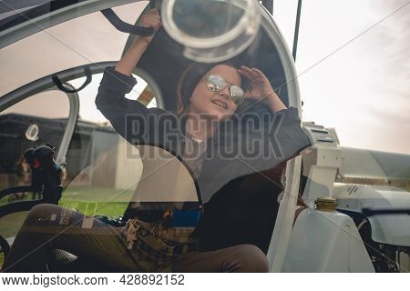 View Through Glass Of Helicopter Cockpit Of Cheerful Tween Girl Looking At Sky