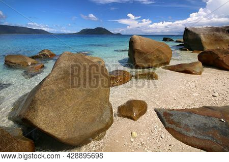 A Rocky Beach Next To A Body Of Water On An Island