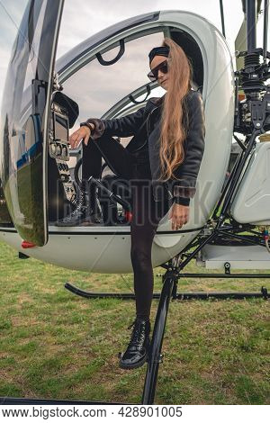 Confident Tween Girl In Black Standing On Footboard Of Helicopter
