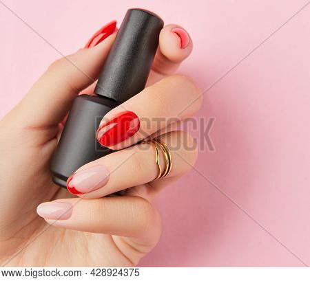 Womans Hand Holding Bottle With Nail Polish Over White Background. Manicure Design Trends