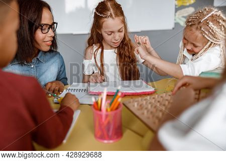 Girl Sitting At The Table And Drawing In A Notebook