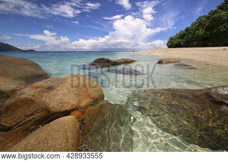 A Rocky Shore Next To A Tropical Body Of Water
