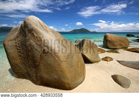 A Rocky Beach Next To A Tropical Body Of Water