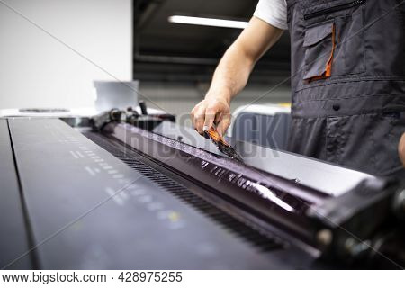 Professional Printing Machine Operator Adding More Color During Print Process In Print Shop.