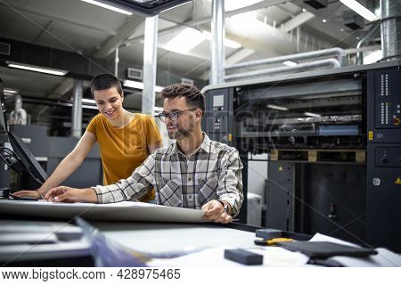 Professional Designers Checking Color Matching And Print Quality In Printing Shop Or Factory.