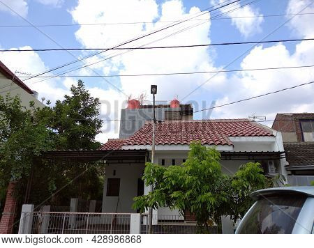 A White House In Indonesia With A Light Blue Avanza In Front Of It