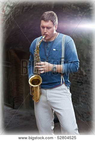Young saxophonist plays on his sax with bright emotions in the street. Serbia.