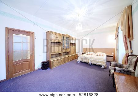 Light bedroom with a double bed, armchair and wall cabinet